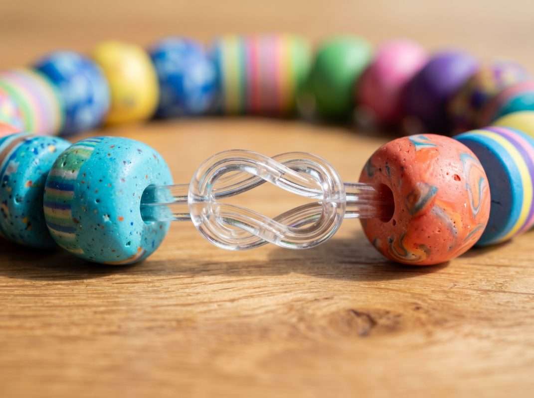Close-up of a finished clay bead bracelet highlighting a secure surgeon's knot tied with 0.8mm clear elastic cord.