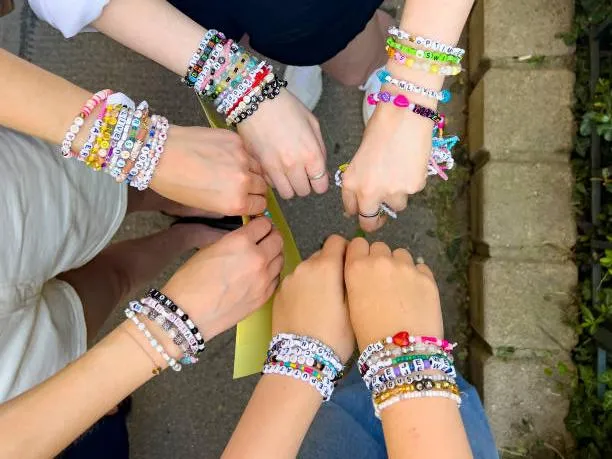 A forearm covered in dozens of beaded bracelets ready to trade