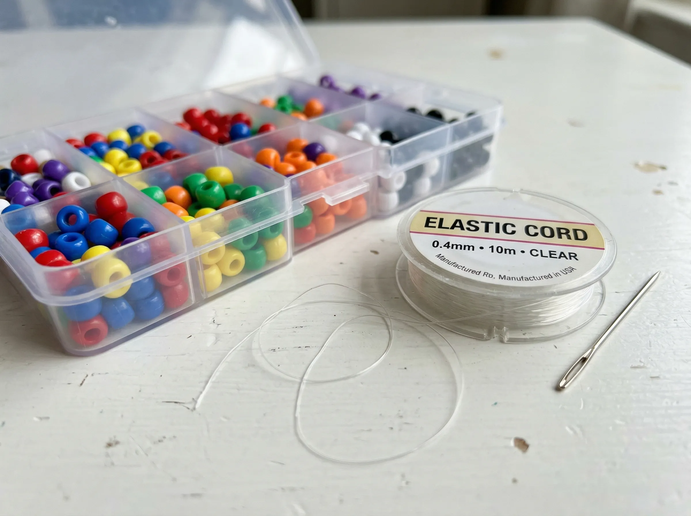A generic budget bead starter set showcasing standard plastic beads and easily breakable 0.4mm thin elastic cord.